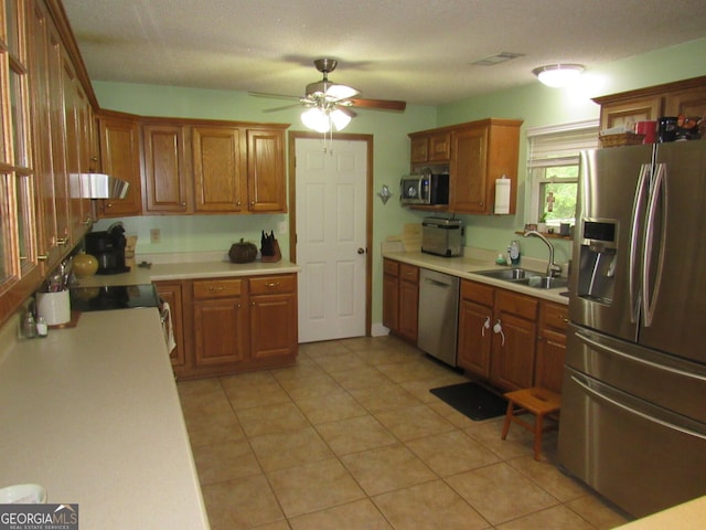 kitchen with light countertops, visible vents, appliances with stainless steel finishes, brown cabinetry, and a sink