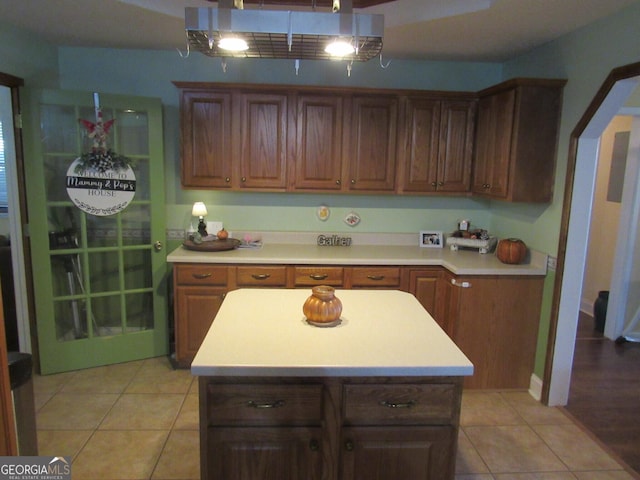 kitchen with light tile patterned floors, arched walkways, light countertops, and a center island