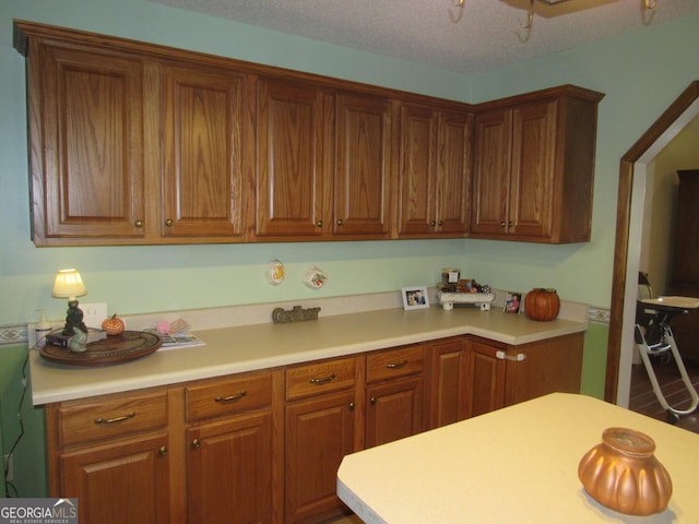 kitchen featuring brown cabinetry, light countertops, and a textured ceiling