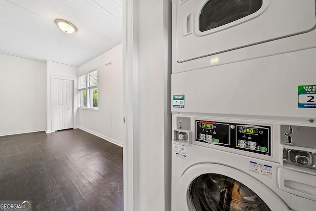 clothes washing area featuring baseboards, dark wood-type flooring, and stacked washer and clothes dryer