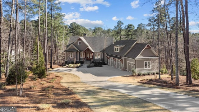 craftsman-style home with a garage, a forest view, and concrete driveway