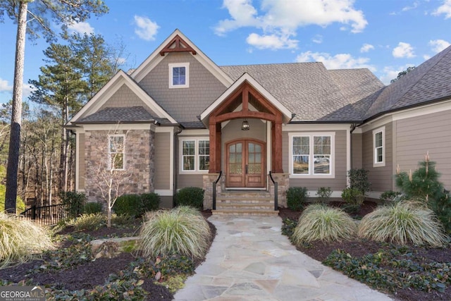 craftsman inspired home featuring stone siding, a shingled roof, and french doors