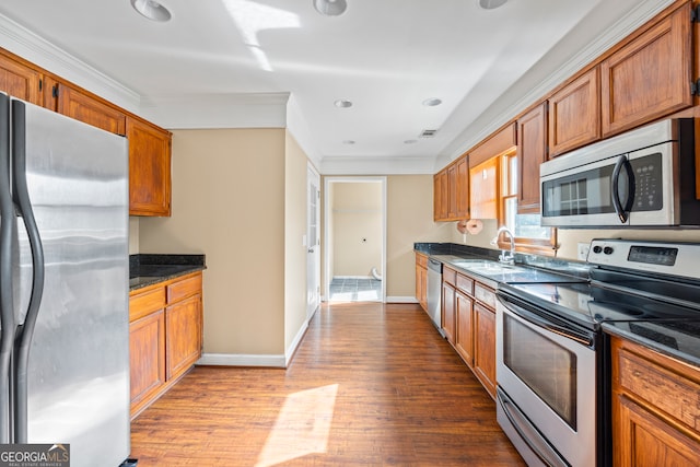 kitchen featuring brown cabinets, stainless steel appliances, dark wood-type flooring, ornamental molding, and a sink