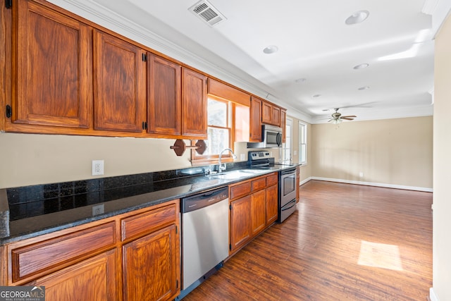 kitchen with dark wood-style flooring, stainless steel appliances, visible vents, a ceiling fan, and a sink