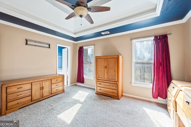 bedroom with a tray ceiling, light carpet, crown molding, and baseboards