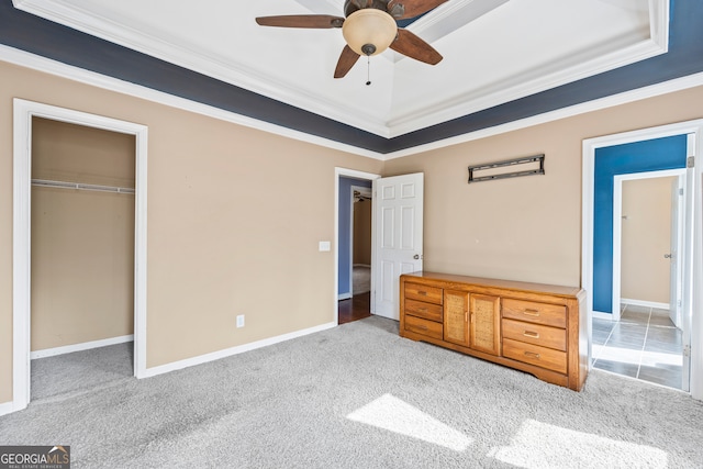 unfurnished bedroom with baseboards, carpet, a tray ceiling, crown molding, and a closet