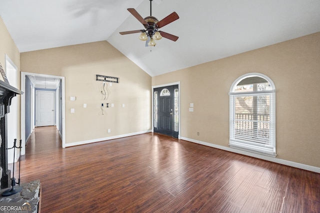 unfurnished living room with dark wood finished floors, a ceiling fan, attic access, high vaulted ceiling, and baseboards