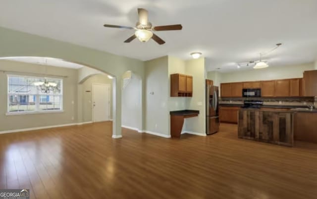 kitchen with dark countertops, dark wood-type flooring, freestanding refrigerator, open floor plan, and black microwave