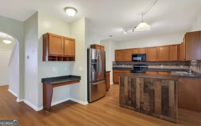 kitchen with dark countertops, decorative backsplash, stove, black microwave, and stainless steel fridge