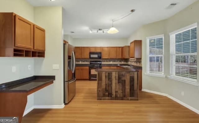 kitchen featuring light wood finished floors, tasteful backsplash, baseboards, dark countertops, and black appliances