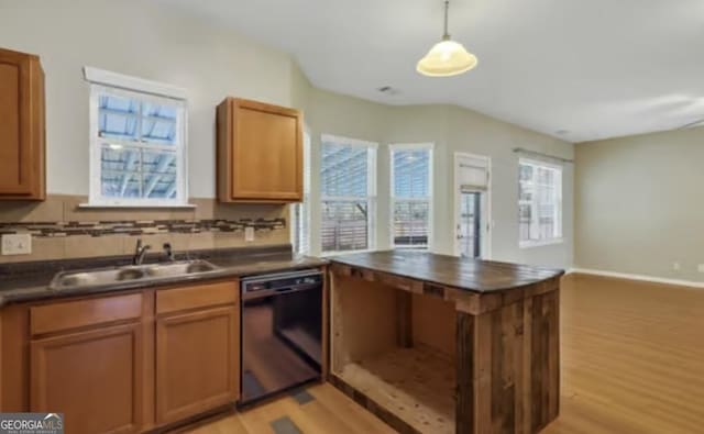 kitchen with light wood-style flooring, a sink, black dishwasher, decorative backsplash, and dark countertops