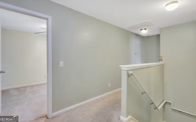 hall featuring carpet floors, baseboards, and an upstairs landing