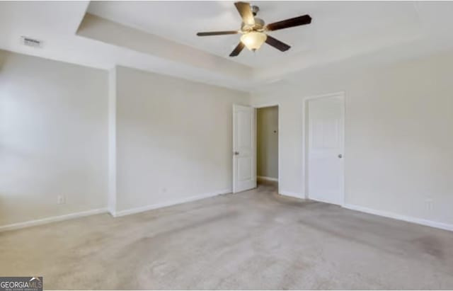 interior space with a raised ceiling, visible vents, ceiling fan, and baseboards