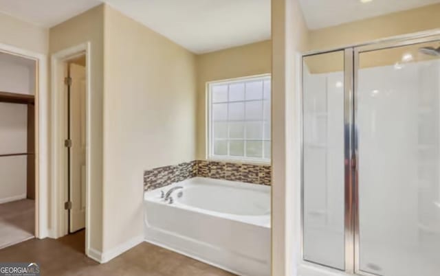 bathroom with a stall shower, a garden tub, and baseboards