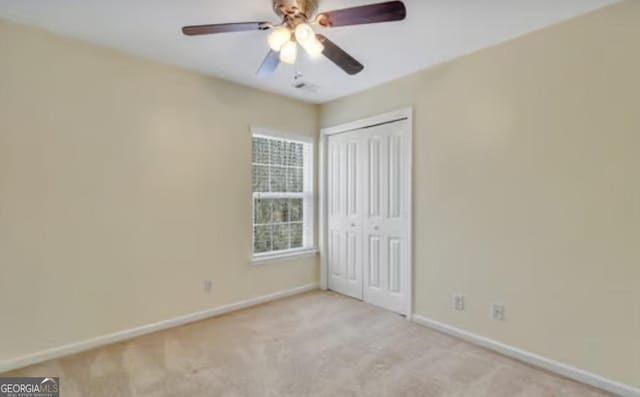 unfurnished bedroom with carpet floors, ceiling fan, baseboards, and a closet