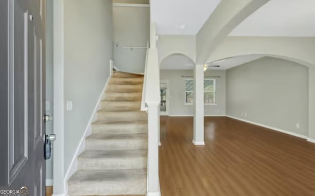 foyer entrance featuring ceiling fan, stairway, arched walkways, and wood finished floors