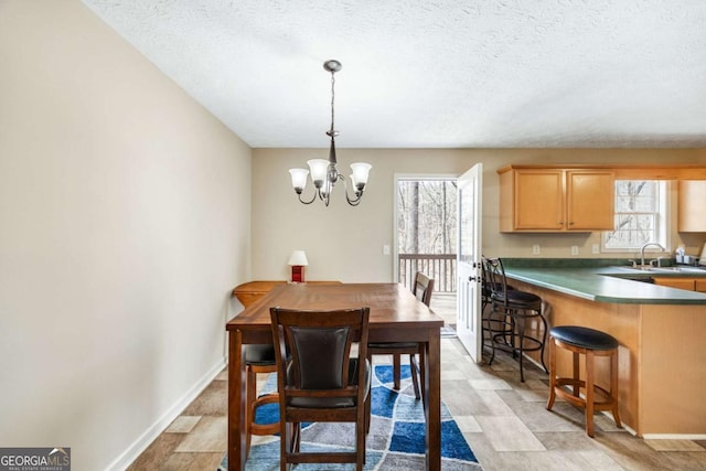 dining room featuring baseboards, a textured ceiling, and an inviting chandelier