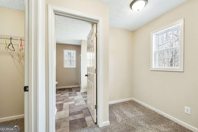 bathroom with a textured ceiling, a spacious closet, and baseboards