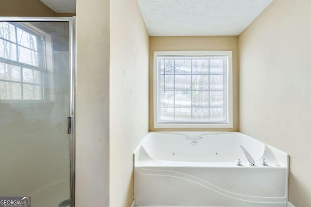 bathroom featuring a jetted tub, a healthy amount of sunlight, a shower stall, and a textured ceiling