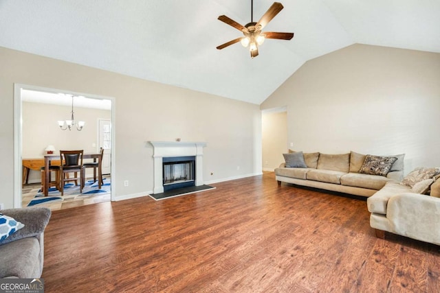 living room with ceiling fan with notable chandelier, a fireplace, vaulted ceiling, and wood finished floors