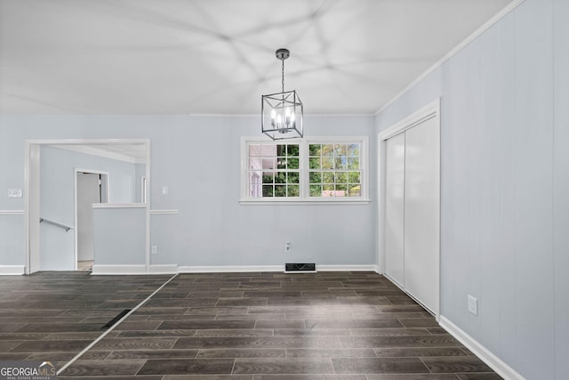 unfurnished dining area with visible vents, baseboards, wood finished floors, an inviting chandelier, and crown molding