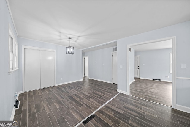 interior space with dark wood-style floors, baseboards, visible vents, and a chandelier