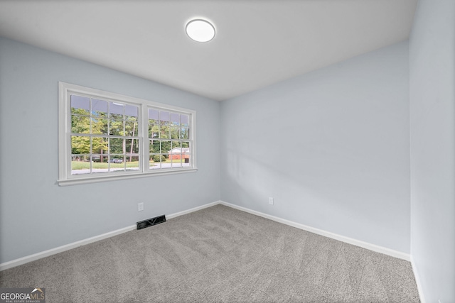 empty room with carpet, visible vents, and baseboards