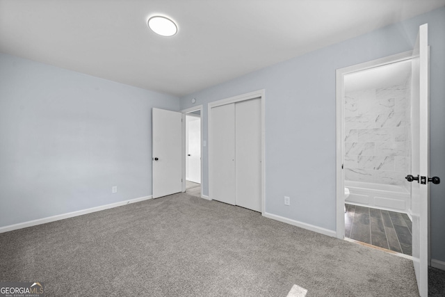 unfurnished bedroom with a closet, carpet flooring, connected bathroom, and baseboards