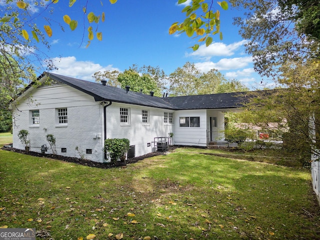 back of property featuring crawl space, brick siding, and a lawn