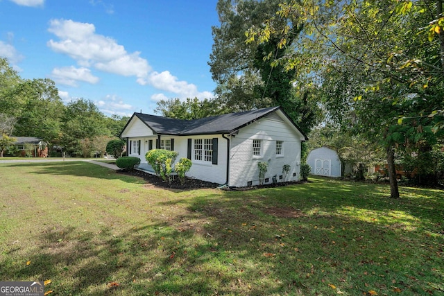 view of front of property featuring brick siding, a storage unit, a front lawn, and an outdoor structure