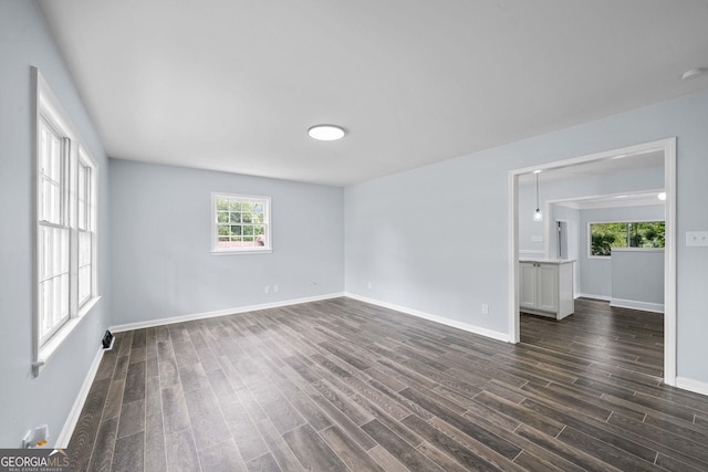 empty room with dark wood-style flooring and baseboards