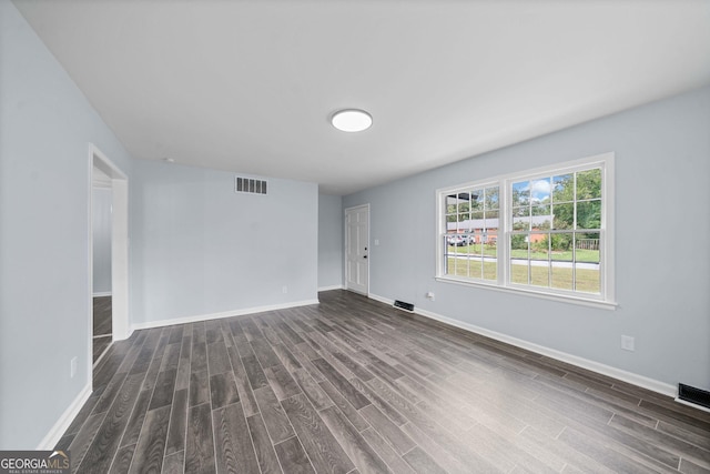 spare room with dark wood-style floors, visible vents, and baseboards