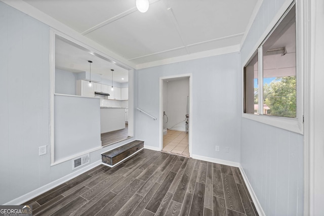 unfurnished living room with dark wood-type flooring, visible vents, and baseboards