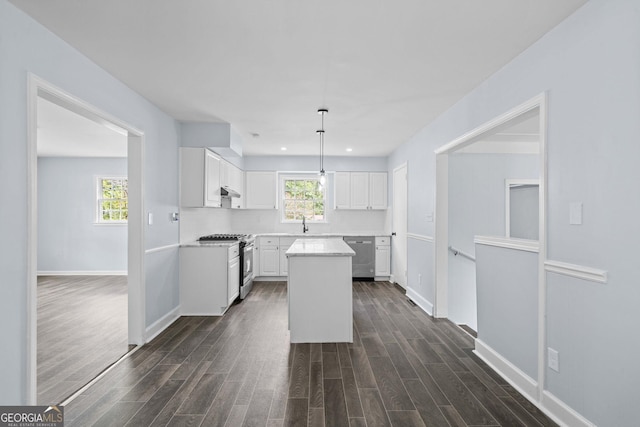 kitchen with dark wood-style flooring, light countertops, appliances with stainless steel finishes, white cabinetry, and a kitchen island