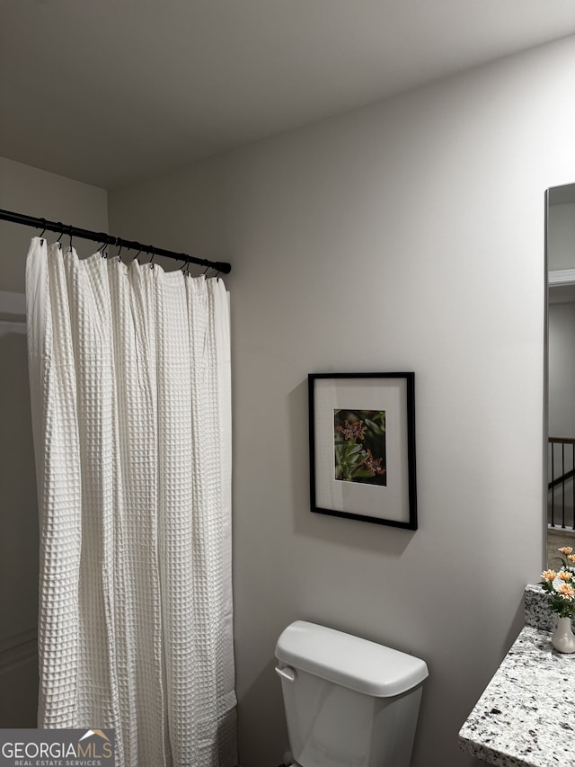 bathroom featuring a shower with curtain, vanity, and toilet