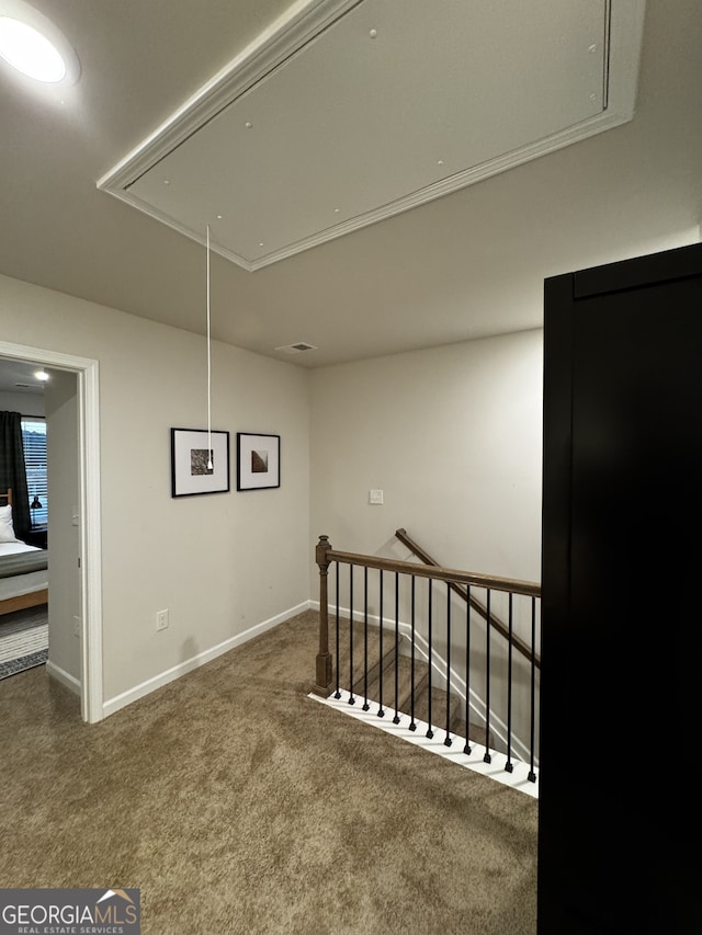 hall featuring attic access, baseboards, carpet floors, and an upstairs landing