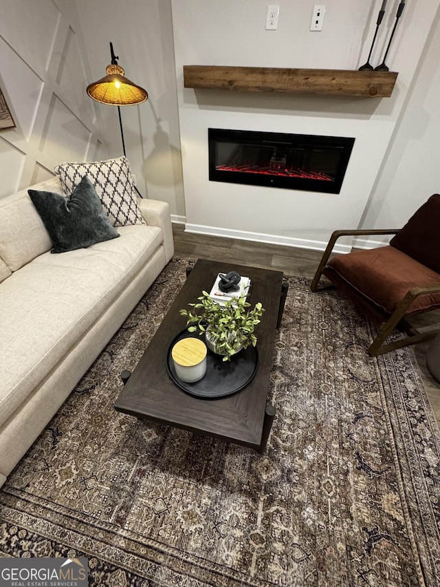 living area with wood finished floors and a glass covered fireplace