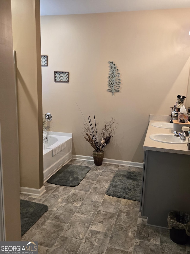 bathroom with double vanity, a washtub, baseboards, and a sink