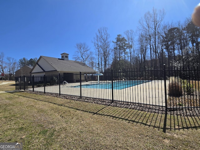 community pool featuring a patio area, a lawn, and fence