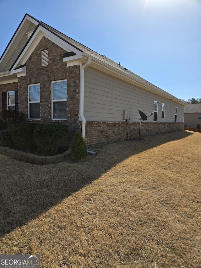 view of property exterior featuring brick siding and a yard