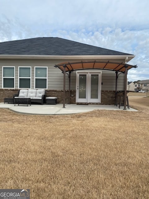 rear view of house with brick siding, a lawn, and a patio area