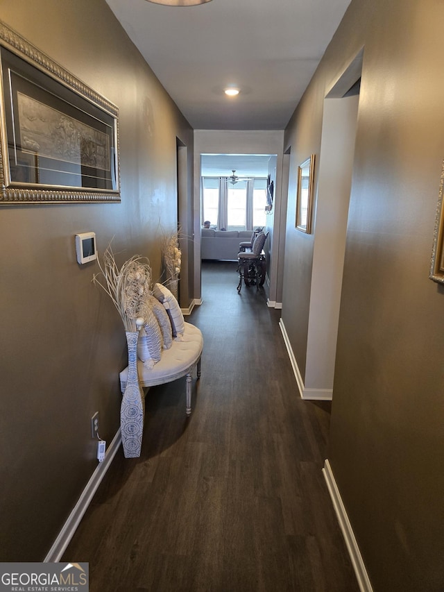 hall with baseboards and wood finished floors