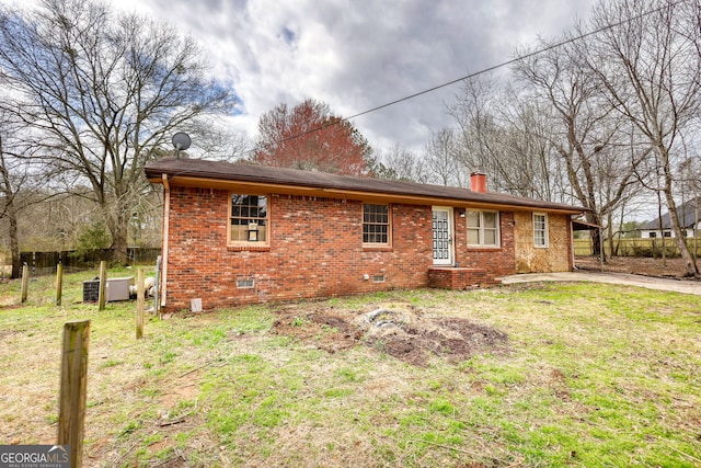 view of front of house with brick siding, a chimney, a front yard, crawl space, and fence