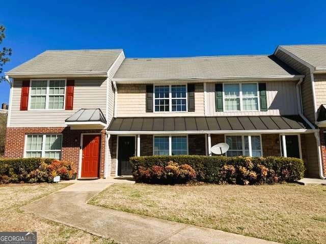 multi unit property featuring a standing seam roof, metal roof, brick siding, and a front lawn