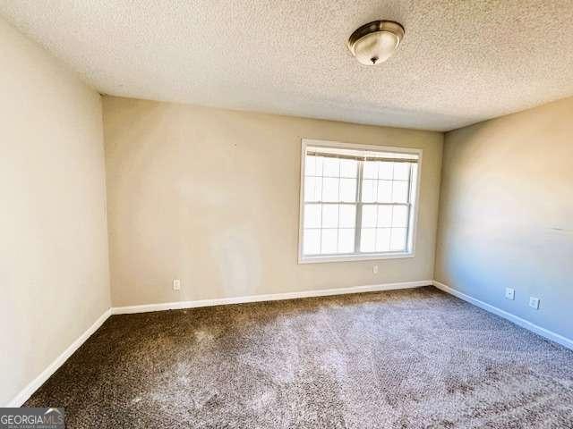 empty room with a textured ceiling and baseboards