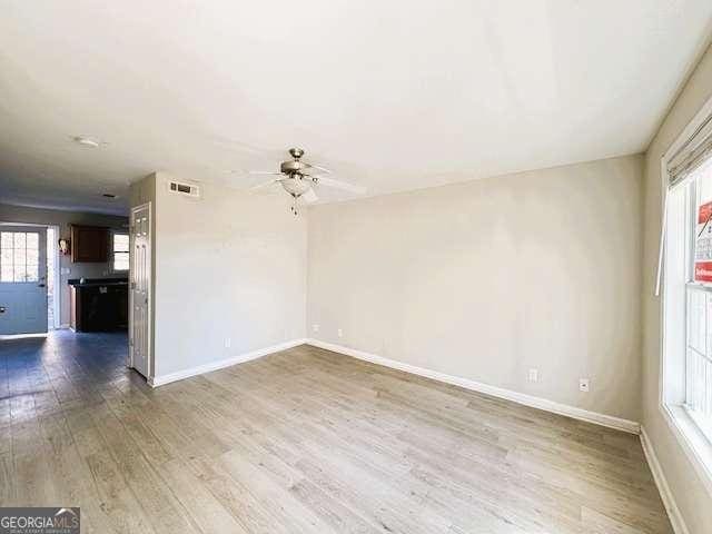 spare room featuring a ceiling fan, wood finished floors, visible vents, and baseboards