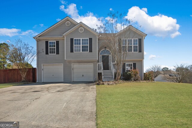 bi-level home with fence, driveway, a front yard, and an attached garage