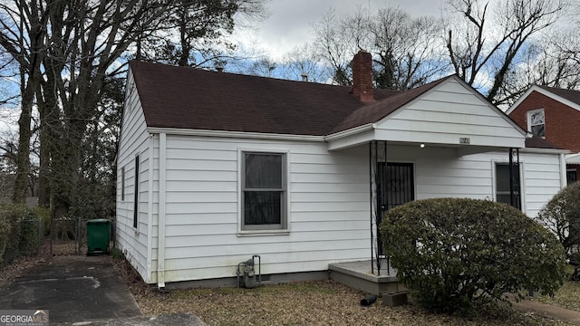 bungalow with roof with shingles and a chimney