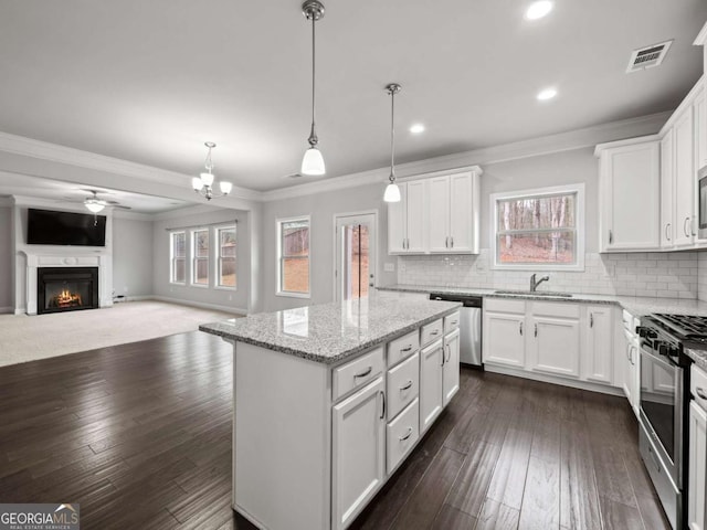 kitchen with tasteful backsplash, a kitchen island, appliances with stainless steel finishes, a lit fireplace, and a sink