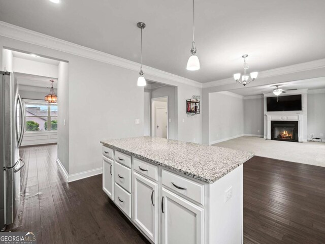 kitchen featuring a lit fireplace, dark wood finished floors, freestanding refrigerator, and a center island